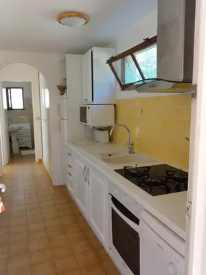 a kitchen with white cabinets and a yellow tile floor at Résidence Les Mandiles in Cargèse