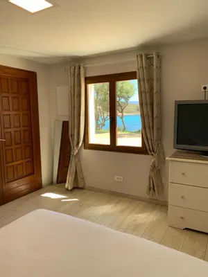 a bedroom with a bed and a television and a window at Résidence Les Mandiles in Cargèse
