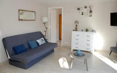 a living room with a blue couch and a table at Résidence Les Mandiles in Cargèse