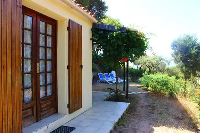 a door to a house with two chairs on a patio at Résidence Les Mandiles in Cargèse
