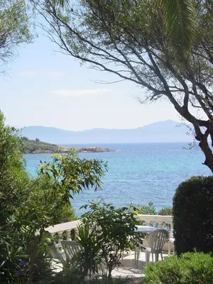 a table and chairs sitting next to the ocean at Résidence Les Mandiles in Cargèse