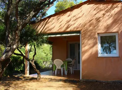 a small orange house with a table and chairs on the porch at Résidence Les Mandiles in Cargèse
