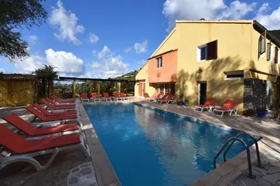 a swimming pool with lounge chairs and a building at Residence Helios in Cargèse