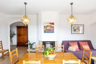 a living room with a purple couch and a dining room at Residence Helios in Cargèse