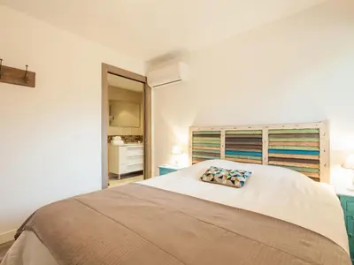 a white bedroom with a large bed and a window at Apartment Château-10 by Interhome in Porto-Vecchio