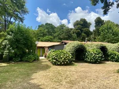 a house in a garden with bushes and trees at Camping Le Sagone in Sagone