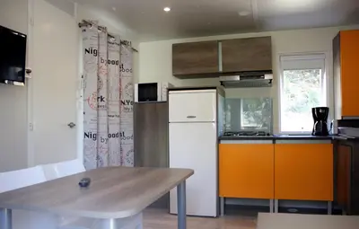a kitchen with a table and a white refrigerator at Camping Le Sagone in Sagone