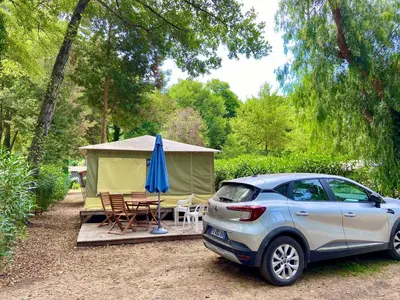 a car parked in front of a tent with a table and a blue umbrella at Camping Le Sagone in Sagone
