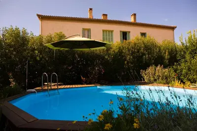 a swimming pool with an umbrella next to a house at A l'ombre du clocher in Calenzana
