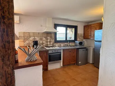 a kitchen with wooden cabinets and a stove top oven at CAROLE F4 in Zonza
