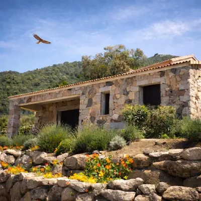 a stone building with a bird flying over a garden at Charmante maison de village *** in Santa-Maria-Figaniella