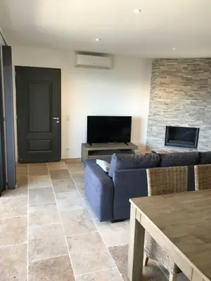 a living room with a blue couch and a tv at Charmante maison de village *** in Santa-Maria-Figaniella