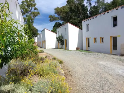 a row of white buildings on a dirt road at FKK-Feriendorf Village naturiste Club Corsicana in Linguizzetta