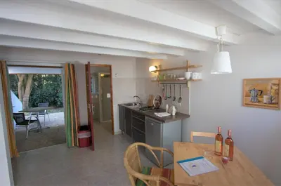 a kitchen with a wooden table and a dining room at FKK-Feriendorf Village naturiste Club Corsicana in Linguizzetta