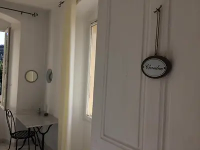 a room with a table and a clock on the door at Casa Eugénie l'appartement de tante Madeleine vue sur les montagnes in Venaco
