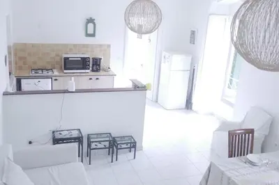 a white living room with a counter and a kitchen at Casa Eugénie l'appartement de tante Madeleine vue sur les montagnes in Venaco