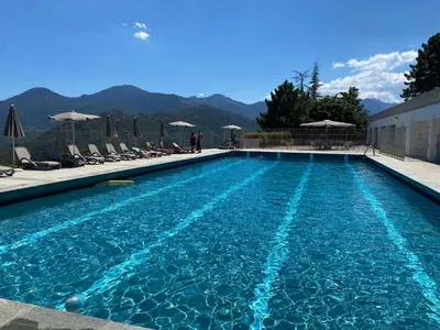a swimming pool with chairs and mountains in the background at Casa Eugénie l'appartement de tante Madeleine vue sur les montagnes in Venaco