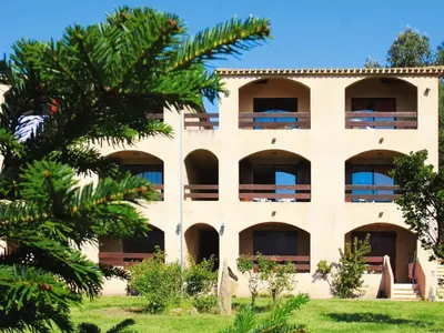 a building with a palm tree in front of it at Residence Les Dauphins in Tiuccia with balcony in Casaglione