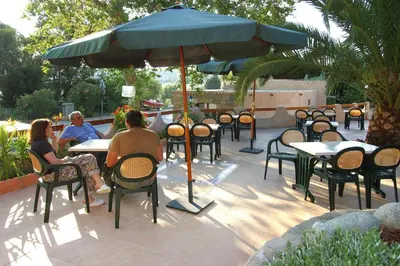 a group of people sitting at tables under an umbrella at Apartment in Corsica near Liscia Beach in Casaglione