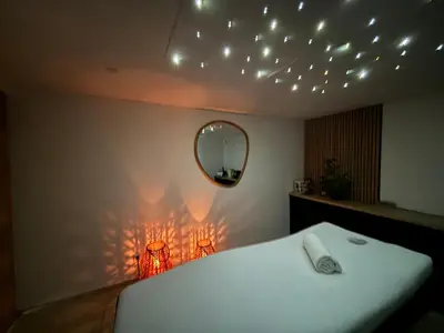 a bedroom with a bed and a mirror and lights at Appartement avec jacuzzi in Porto-Vecchio