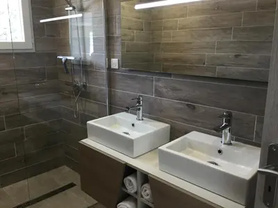 a bathroom with two sinks and a shower at Appartement avec jacuzzi in Porto-Vecchio