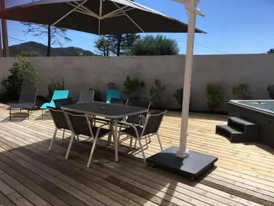 a table and chairs with an umbrella on a deck at Appartement avec jacuzzi in Porto-Vecchio