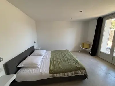 a bedroom with a large bed and a window at Appartement avec jacuzzi in Porto-Vecchio