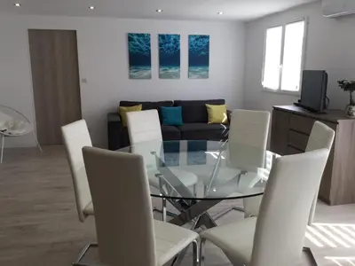 a living room with a glass table and white chairs at Appartement avec jacuzzi in Porto-Vecchio