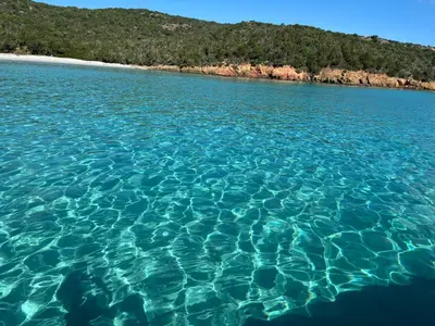 a large body of blue water next to a beach at Appartement avec jacuzzi in Porto-Vecchio