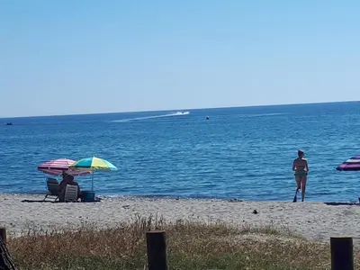 two people sitting under umbrellas on a beach at Casa Padulella in Moriani Plage