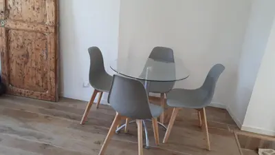 a glass table with four gray chairs around it at Casa Padulella in Moriani Plage
