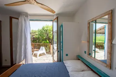 a bedroom with a bed and a sliding glass door at Residence Fium Del Cavo in Sainte-Lucie de Porto-Vecchio