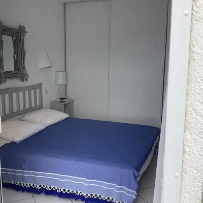 a bedroom with a bed with a blue blanket at Residence Fium Del Cavo in Sainte-Lucie de Porto-Vecchio
