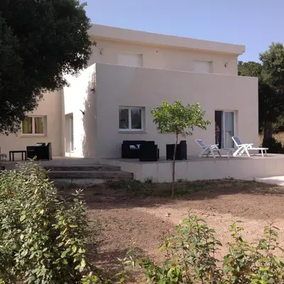 a white house with two chairs in front of it at Chambre d'hôte l'Escale in Sainte-Lucie de Porto-Vecchio