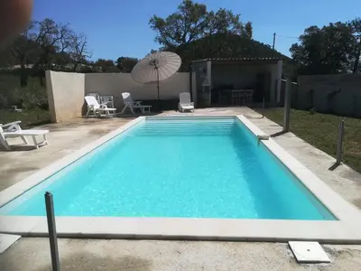 a swimming pool in a yard with an umbrella at Chambre d'hôte l'Escale in Sainte-Lucie de Porto-Vecchio