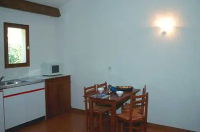 a kitchen with a table and two chairs and a kitchen with a sink at Résidence Mari di Soli in Porto-Vecchio