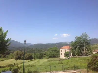 a house on a hill with mountains in the background at Hotel Clair de Lune in Zonza