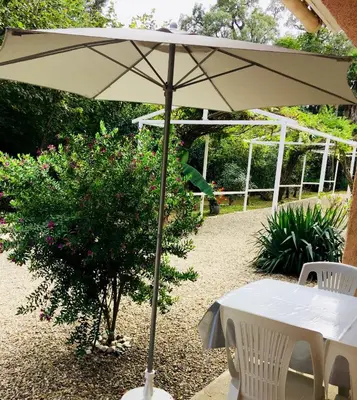 a white table with an umbrella in a garden at Résidence EMILIA in Santa-Maria-Poggio