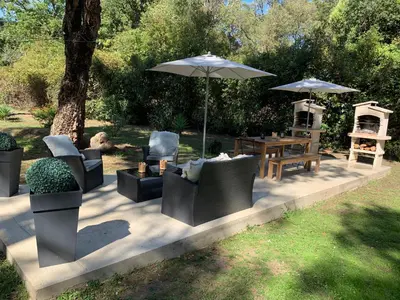 a patio with chairs and an umbrella and a table at Résidence EMILIA in Santa-Maria-Poggio