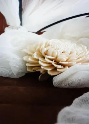 a person wearing white gloves holding a white flower on a bed at Aux Bords du Temps in Zonza