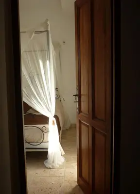 a woman in a white wedding dress standing in front of a bed at Aux Bords du Temps in Zonza