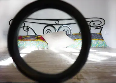 a mirror reflection of a bed with a white pillow at Aux Bords du Temps in Zonza