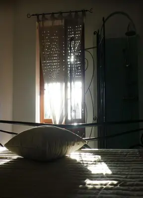a bed with a pillow in front of a window at Aux Bords du Temps in Zonza