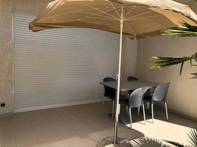 a table and chairs under an umbrella in a room at Porticcio centre plage à pieds, studio-cabine 4 Pers max, promo 7 nuits in Porticcio