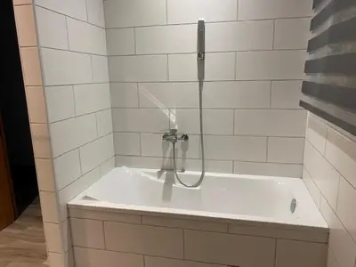 a shower in a white tiled bathroom with a tub at La Villa Volpaso in Belgodère
