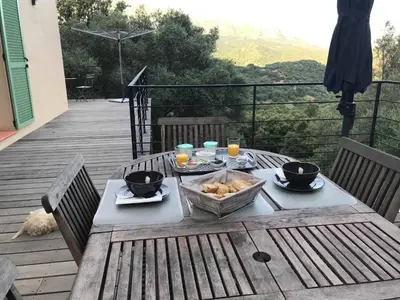 a table with food and drinks on a wooden deck at La Villa Volpaso in Belgodère