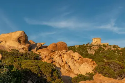 a pile of rocks with a lighthouse on a mountain at HOTEL CAMPOMORO in Campomoro