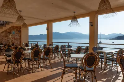 a restaurant with tables and chairs with a view of the water at HOTEL CAMPOMORO in Campomoro