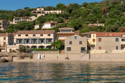 a group of houses on a hill next to the water at HOTEL CAMPOMORO in Campomoro