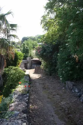a dirt road with a bridge and some bushes and trees at costa di sognu in Costa